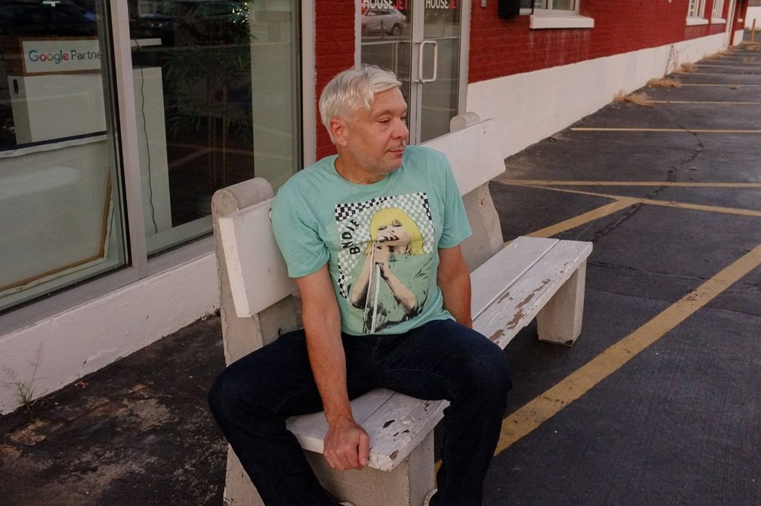 Gabriel Ramsey in a teal t-shirt, seated on a bench.