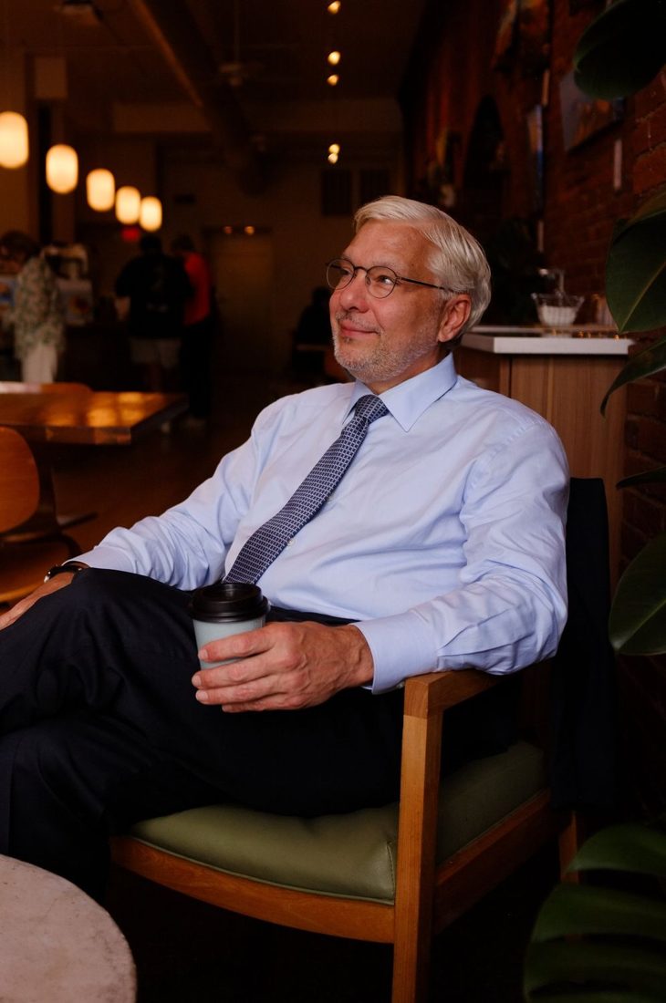 Gabriel Ramsey in a light blue shirt and tie, seated in a café.